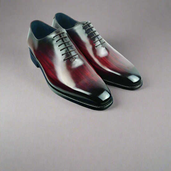 Pair of polished dress shoes on a blue box with a white background
