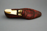 Red leather shoe with a wooden sole on a wooden surface