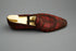 Red leather shoe with a wooden sole on a wooden surface