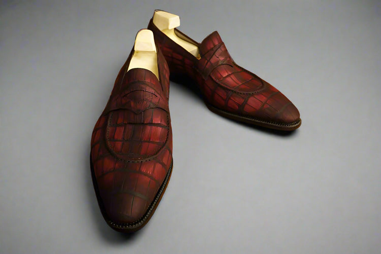 Pair of maroon loafers on a wooden surface
