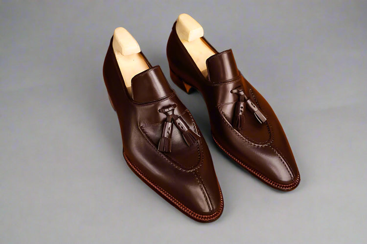 Pair of brown leather loafers with tassels on a wooden surface