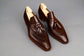 Pair of brown leather loafers with tassels on a wooden surface