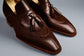 Pair of brown leather loafers with tassels on a wooden surface