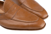 Close-up of a pair of tan leather penny loafers with a pebbled texture, showing the toe and side panels against a white background.