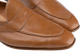 Close-up of a pair of tan leather penny loafers with a pebbled texture, showing the toe and side panels against a white background.