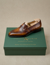 A single brown leather loafer shoe with a tan insole, displayed on top of a dark green shoebox with the brand name 'Italianxquisito' printed in gold.