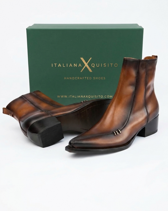A pair of brown leather pointed-toe ankle boots with low block heels, displayed in front of their dark green Italiana Xquisito brand box on a white background.